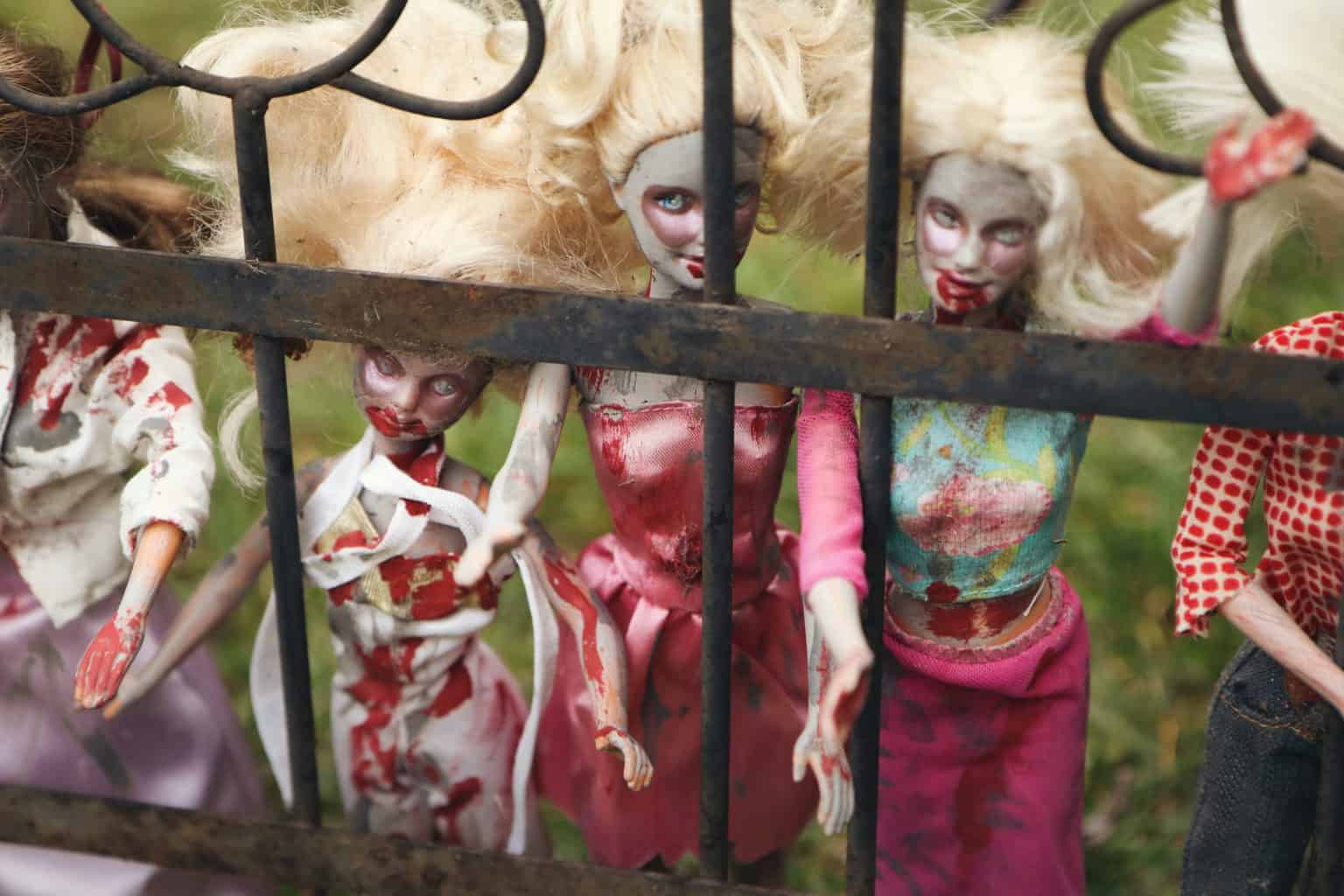 Scary looking dolls displayed on rusty fence