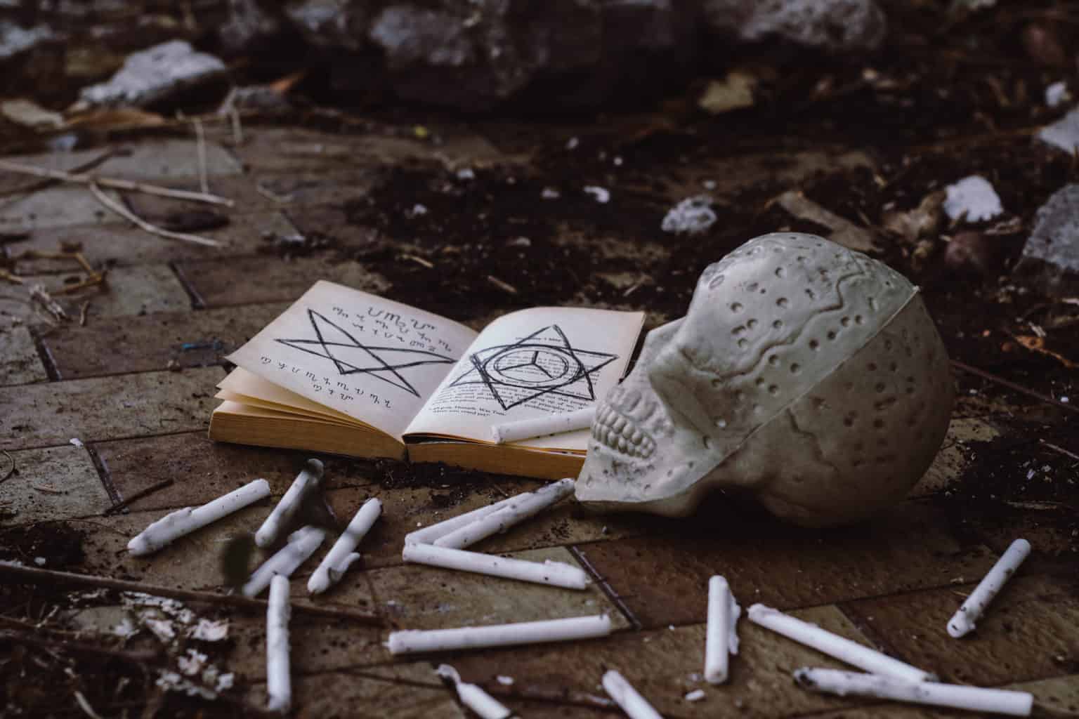 Opened book near skull lying on the ground