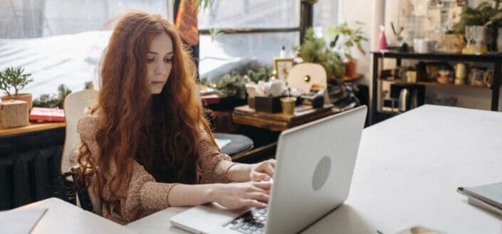 Redhead girl typing into her laptop
