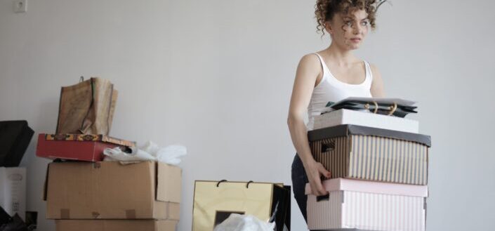Concentrated woman carrying stack of cardboard boxes for relocation