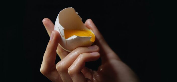 person holding broken egg