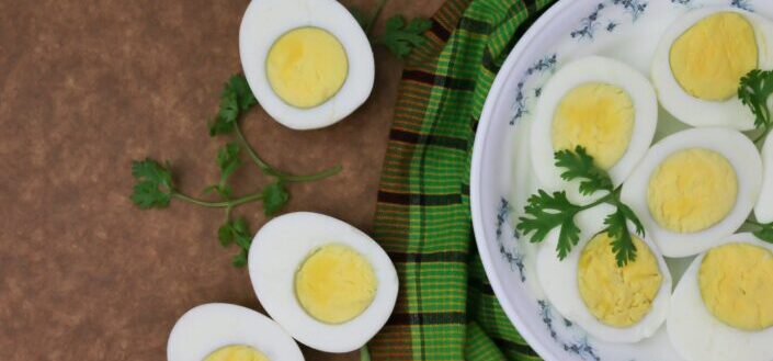 Sliced boiled eggs on plate with parsley leaves