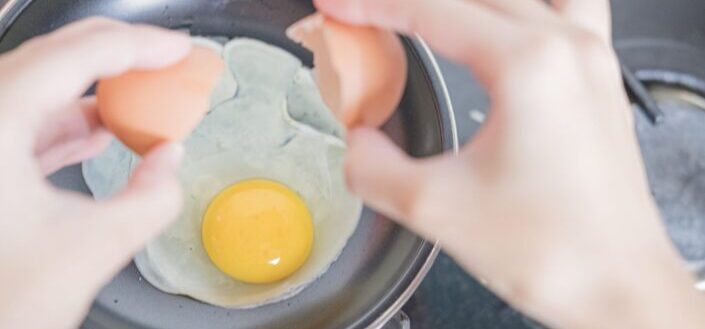 person cooking egg on black frying pan