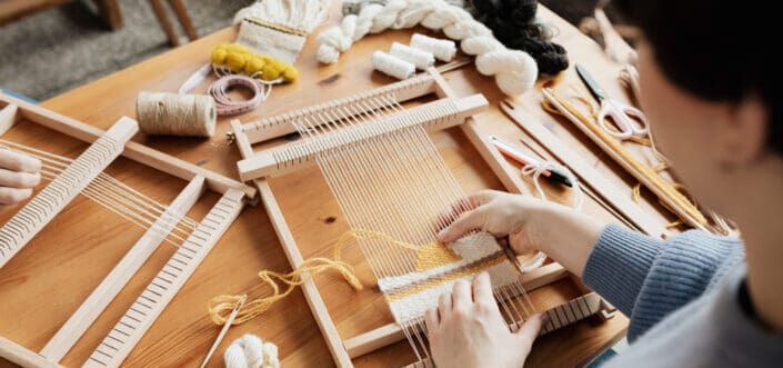 A woman weaving on a table.