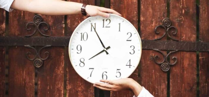round white analog clock held by person
