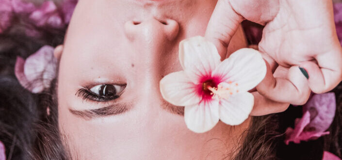 Girl holding a piece of flower by her eye