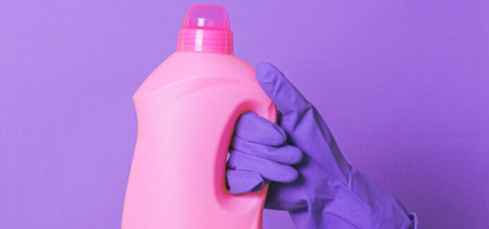 Hand With Purple Glove Holding a Pink Bottle of Cleaning Product