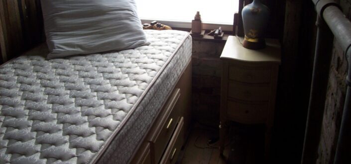 Mattress and Night Stand in Front of Window
