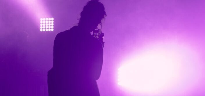 Man performing on a stage with purple lights