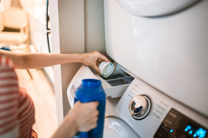 Person Pouring Detergent in a Washing Machine